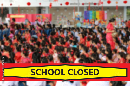 Blurred background of a crowd of Chinese school children sitting in assembly and includes a banner that reads School Closed.