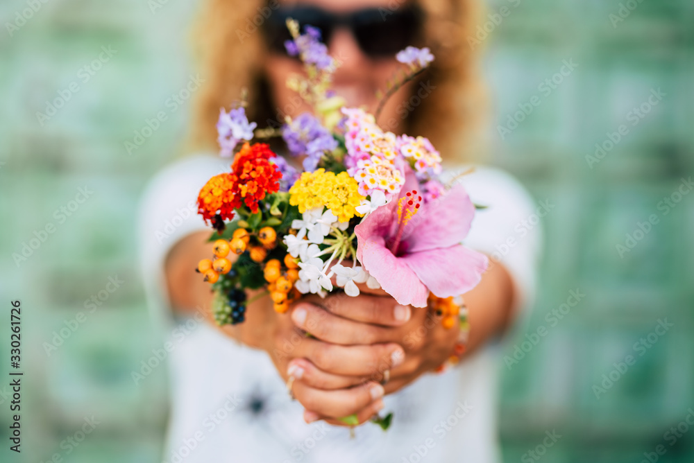 Close up of group of coloured flowers like natural easy nice bouquet - wedding and celebration concept for women's day - defocused unrecognizable woman in background Close up of group of coloured flowers like natural easy nice bouquet - wedding and celebration concept for women's day - defocused unrecognizable woman in background