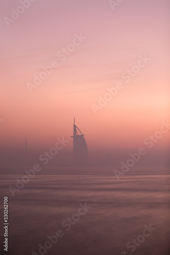 Dawn colors over the Dubai Jumeirah disctrict cityscape on a hazy day. Palm Jumeirah, Dubai, United Arab Emirates.