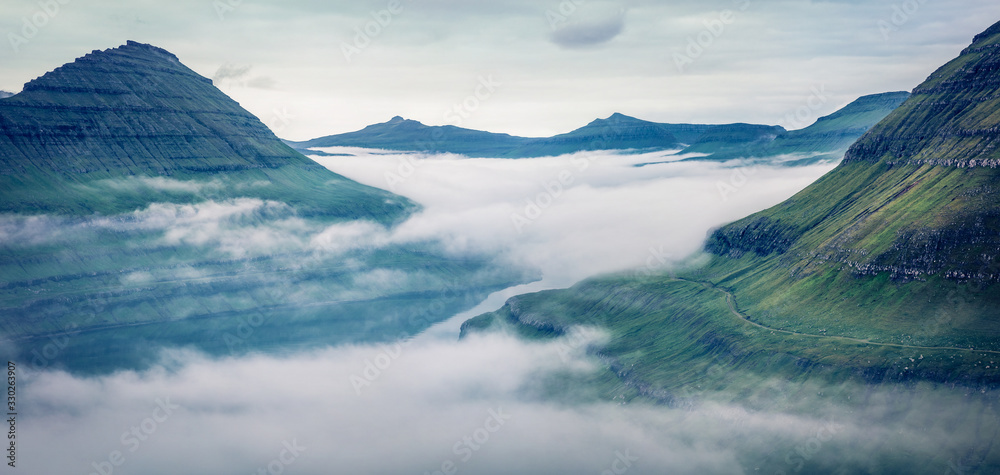 Fototapeta Dramatyczny ranku widok Faroe wyspy z niskimi chmurami, Dani, Europa z niskimi chmurami. Panoramiczna scena letnia wyspy Eysturoy, lokalizacja wioski Funningur. Piękno natury pojęcia tło.