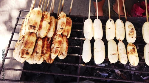 Close up shots of cardava banana on bbq fire stand with skewers. photo