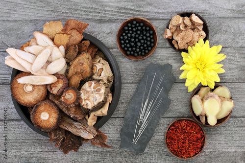 Obraz na plátně Traditional Chinese herbs, acupuncture needles and tablets to boost chi level used in herbal medicine on rustic wood background