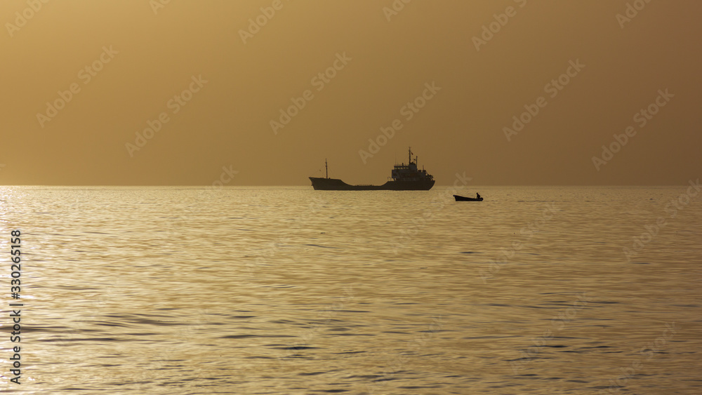 Evening drift of a ship and fisherman's boat off coast of Adriatic