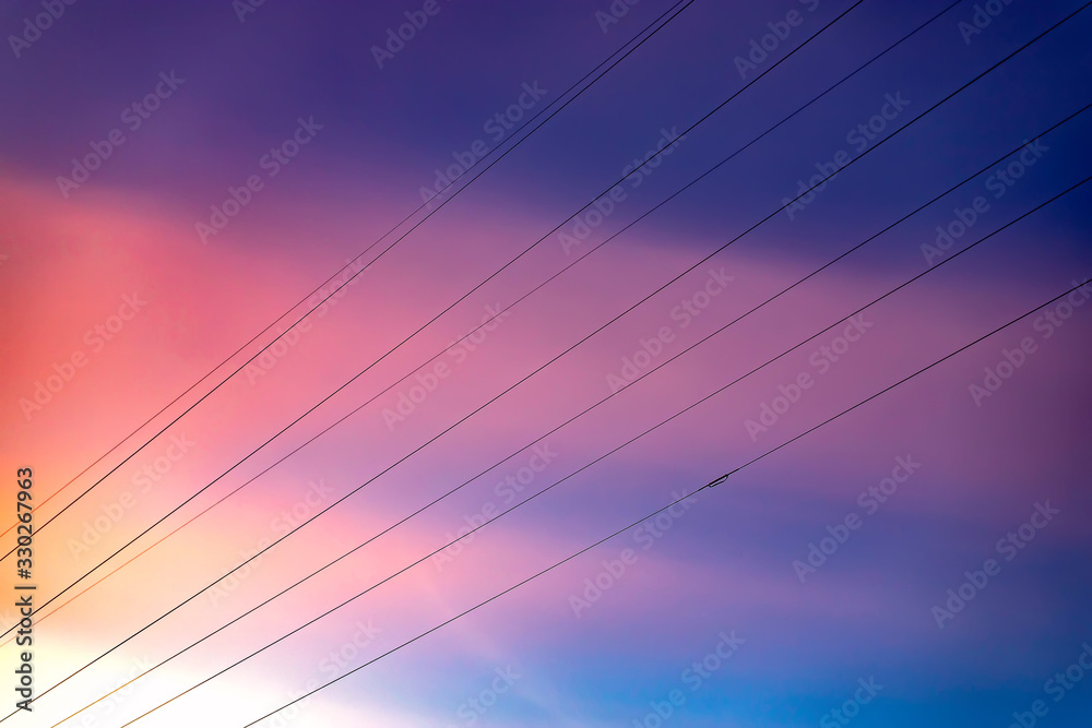 The pink blue sky at sunset. Wires against the sky.