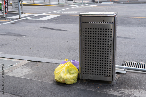 trash bags next to an overflowing rubbish bin in Melbourne city, Australia