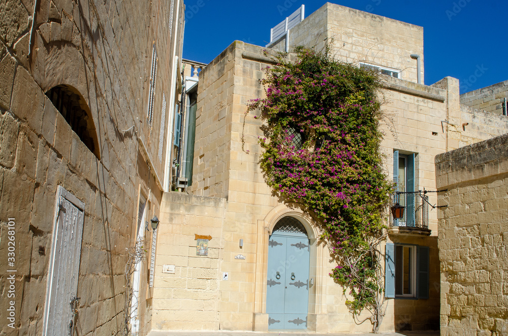 Flowers over door of traditional stone house Mdina Malta