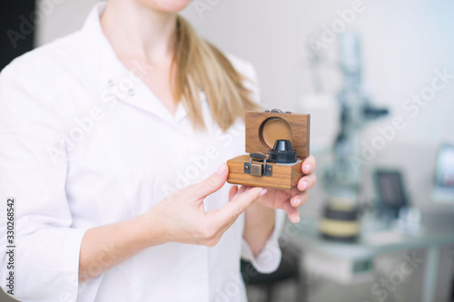 Doctor ophthalmologist surgeon holds Indirect Ophthalmoscopy Lens which used in ophthalmic practice for the general diagnosis of eye diseases and specifically for Selective Laser Trabeculoplasty photo