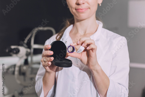 Ophthalmologist surgeon holds in his hands Indirect Ophthalmoscopy Lens which is used in ophthalmic for the general diagnosis of eye diseases and specifically for Selective Laser Trabeculoplasty photo
