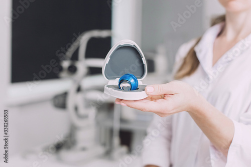 Ophthalmologist surgeon holds in his hands Indirect Ophthalmoscopy Lens which is used in ophthalmic for the general diagnosis of eye diseases and specifically for Selective Laser Trabeculoplasty photo