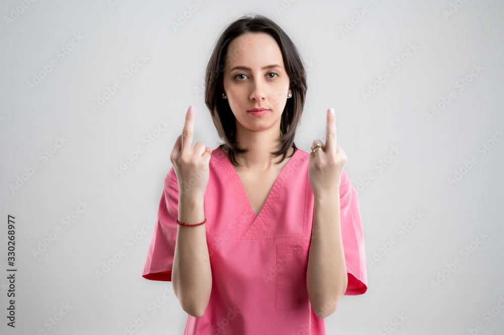 Young woman medical professional nurse or doctor dressed with pink hospital clothes showing double fuck you Young woman medical professional nurse or doctor dressed with pink hospital clothes showing double fuck you