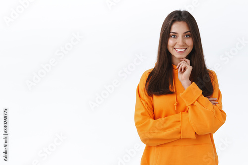 Curious beautiful caucasian woman looking at interesting thing, touch chin and smiling pleased, found excellent product, consider buy, hear interesting idea, standing intrigued white background