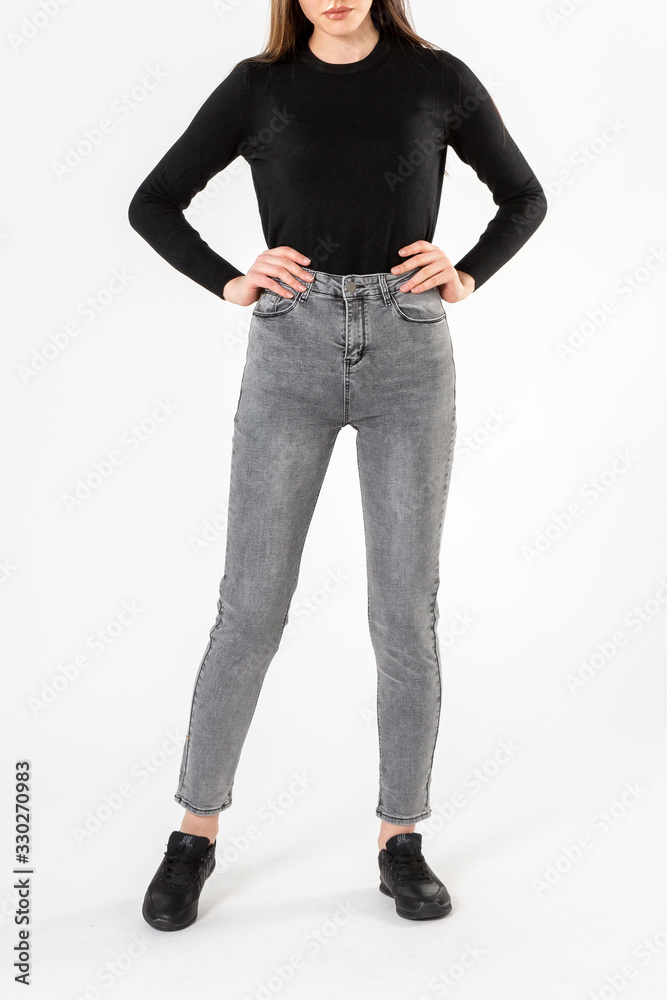 girl in jeans shows jeans on a white background close-up, gray jeans girl in jeans shows jeans on a white background close-up, gray jeans