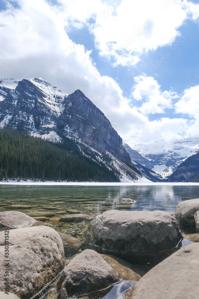 Fototapeta premium Mount fairview, partly frozen lake, rocks in foreground. Lake Louise Banff National Park, Alberta Canada
