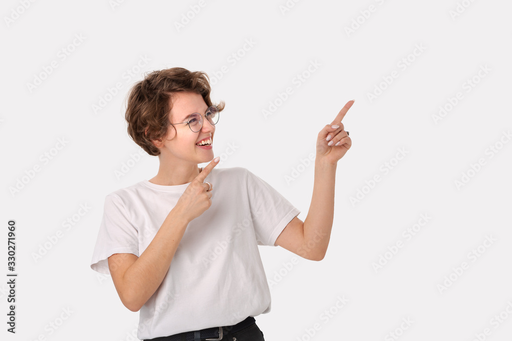 Pretty smiling woman in white shirt and eyeglasses pointing at copy space Pretty smiling woman in white shirt and eyeglasses pointing at copy space