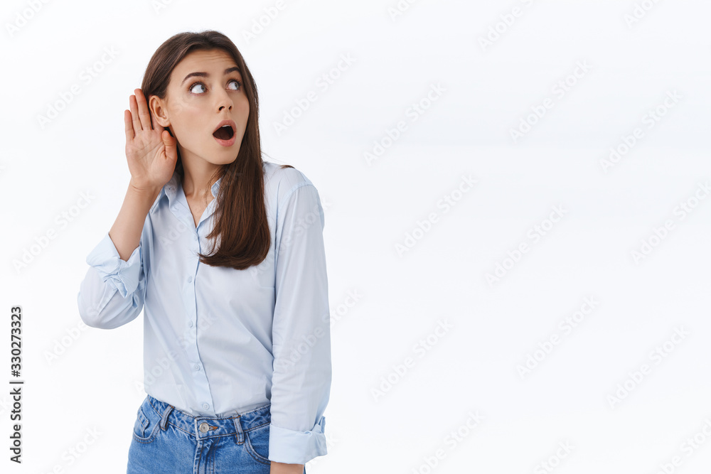 Intrigued and curious female office worker overhear interesting conversation, hold hand near ear and lean left side copy space to hear what person say, gasping shocked as gossiping, white background Intrigued and curious female office worker overhear interesting conversation, hold hand near ear and lean left side copy space to hear what person say, gasping shocked as gossiping, white background