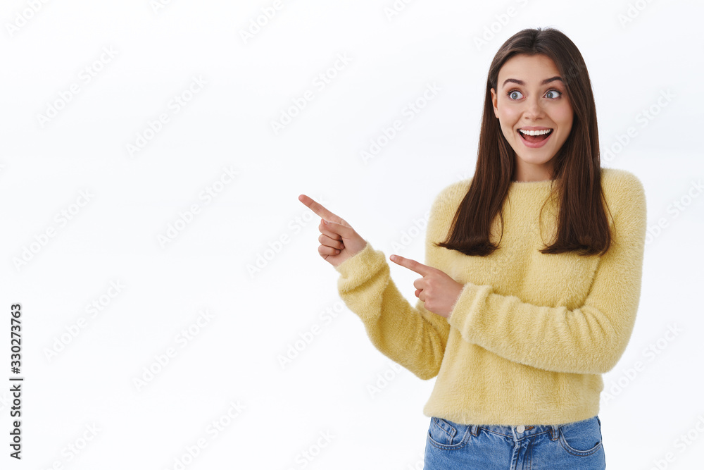 Excited and surprised young happy woman in yellow sweater, drop jaw gasping in awe and astonished pointing looking left side blank space for your promo, standing white background fascinated Excited and surprised young happy woman in yellow sweater, drop jaw gasping in awe and astonished pointing looking left side blank space for your promo, standing white background fascinated