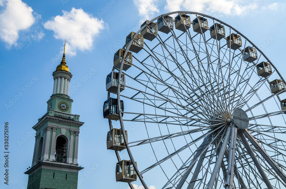 Ferris wheel in historical part of Kyiv. The bell tower of the former Greek monastery at the background. One of the most favorite squares among the locals. The Kontraktova Square. Kyiv, Ukraine