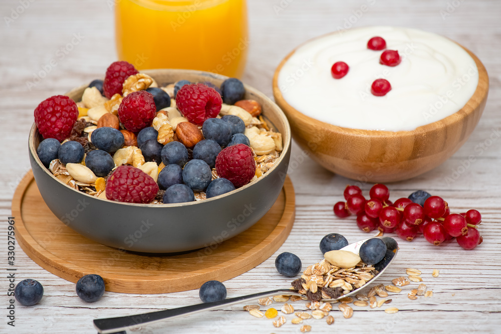 Bio Fruit Blueberry in bowl wood and Natural yogurt, kiwi, Raspberry, and nuts for health and diet with vitamin c in close-up on the wood table. Bio Fruit Blueberry in bowl wood and Natural yogurt, kiwi, Raspberry, and nuts for health and diet with vitamin c in close-up on the wood table.