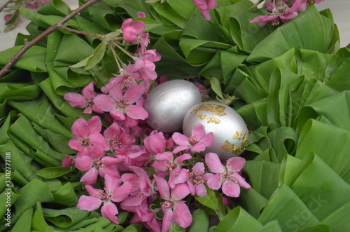 Beautiful festive wreath of green leaves with pink flowers and silver eggs. easter plants