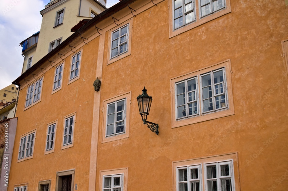 Isolate black street lantern hanging on an orange building wall (Prague, Czech Republic, Europe)