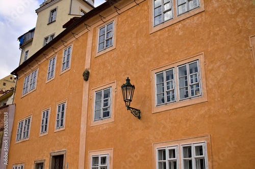 Isolate black street lantern hanging on an orange building wall (Prague, Czech Republic, Europe)