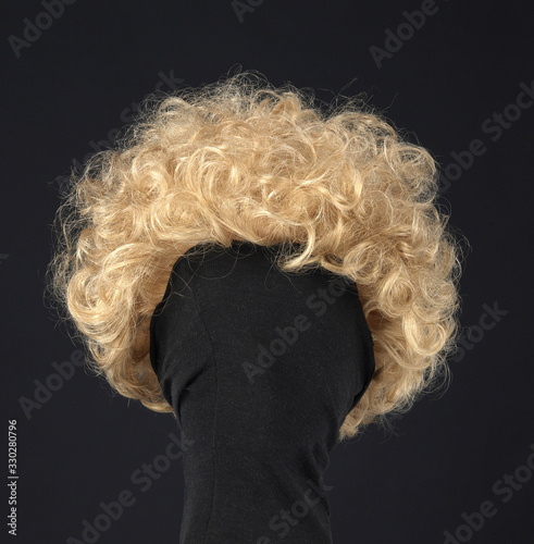 Curly blond hair wig on black background