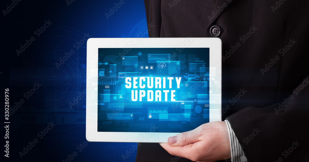 Young business person working on tablet and shows the digital sign: SECURITY UPDATE Young business person working on tablet and shows the digital sign: SECURITY UPDATE