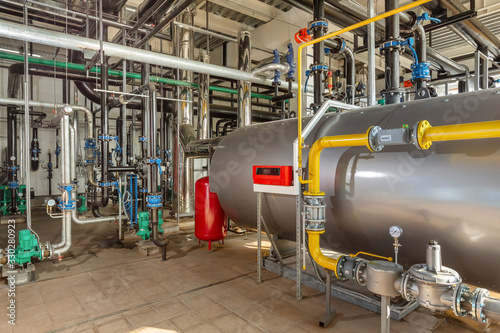 Interior of an industrial boiler room with boilers, many pipes, valves and sensors