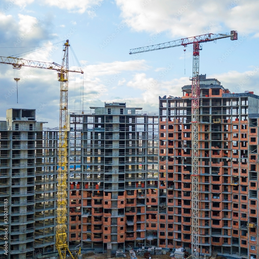 Close-up aerial view of construction site of a new residential area with tower or jib cranes.. Close-up aerial view of construction site of a new residential area with tower or jib cranes..