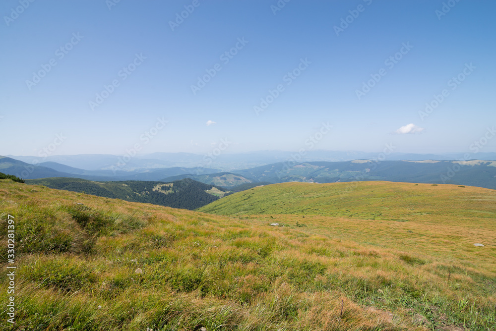 view of the mountains in the Ukrainian Carpathians, green grass and mountains in blue haze, Mountain meadow and blue sky, 
