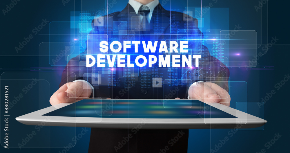 Fototapeta premium Young business person working on tablet and shows the inscription: SOFTWARE DEVELOPMENT