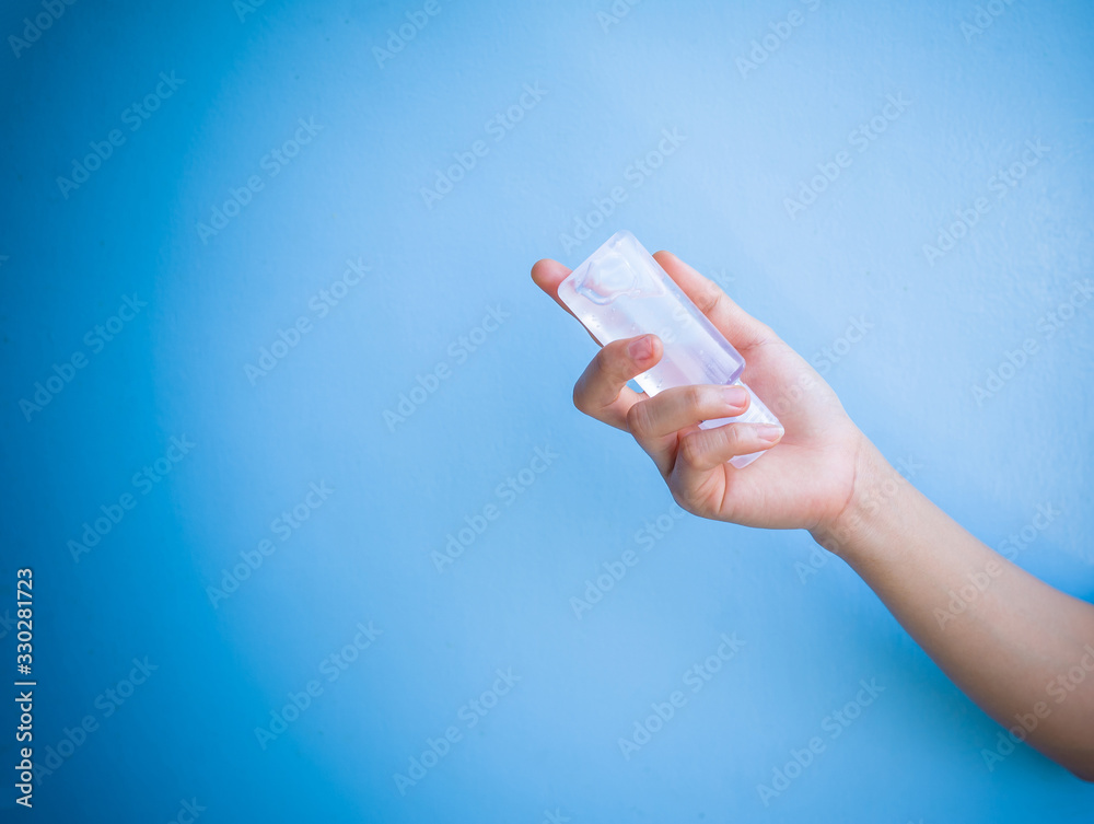 one women hand is carrying alcohol gel for washing hands to protect ...
