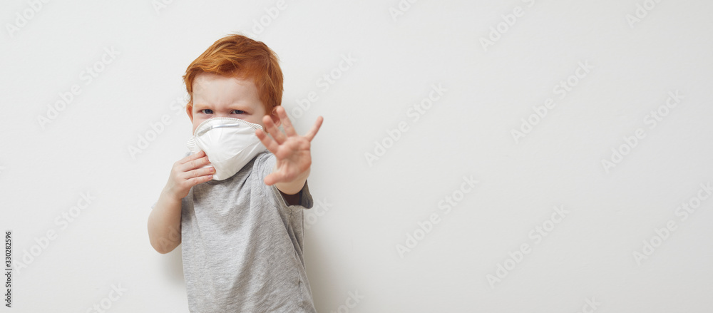 Redhead boy is saying stop and holding his hands up infront of him to Stop Corona virus Covid-19 / 2019nCov while wearing a protecting mask. Redhead boy is saying stop and holding his hands up infront of him to Stop Corona virus Covid-19 / 2019nCov while wearing a protecting mask.