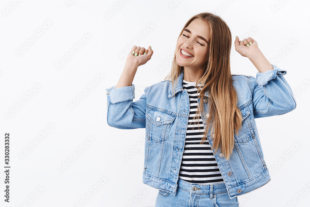 Happy and pleased cheerful blond girl celebrating victory, smiling joyfully with closed eyes, delighted expression, lift hands up fist pump in cheer, celebrating win, great news, become champion
