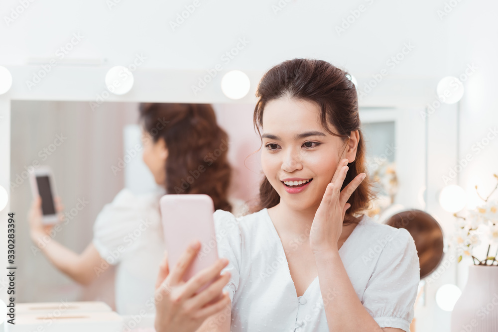 Woman makes selfie in makeup mirror with lamps