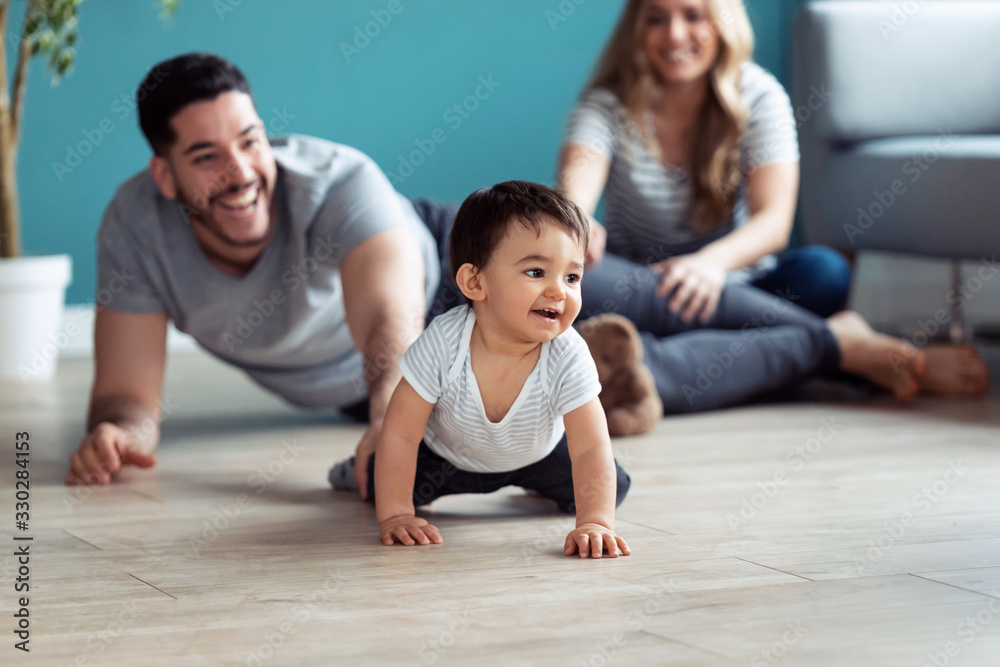 Pretty young parents playing with baby son while sitting on the floor at home. Pretty young parents playing with baby son while sitting on the floor at home.