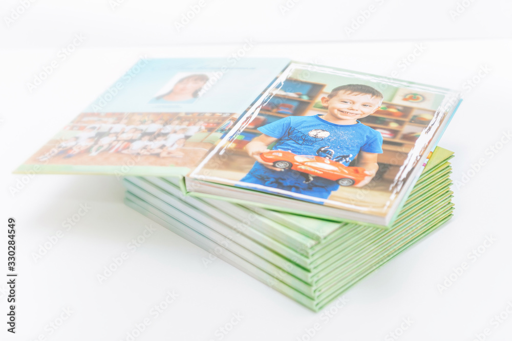graduation photo album of a smiling boy from kindergarten. memorable children's photos are printed in the album. albums on a light background graduation photo album of a smiling boy from kindergarten. memorable children's photos are printed in the album. albums on a light background