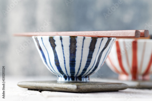 Wooden Chopsticks and ceramic Bowls on bright background.