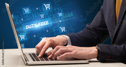 Businessman working on laptop with DUTY-FREE inscription, online shopping concept