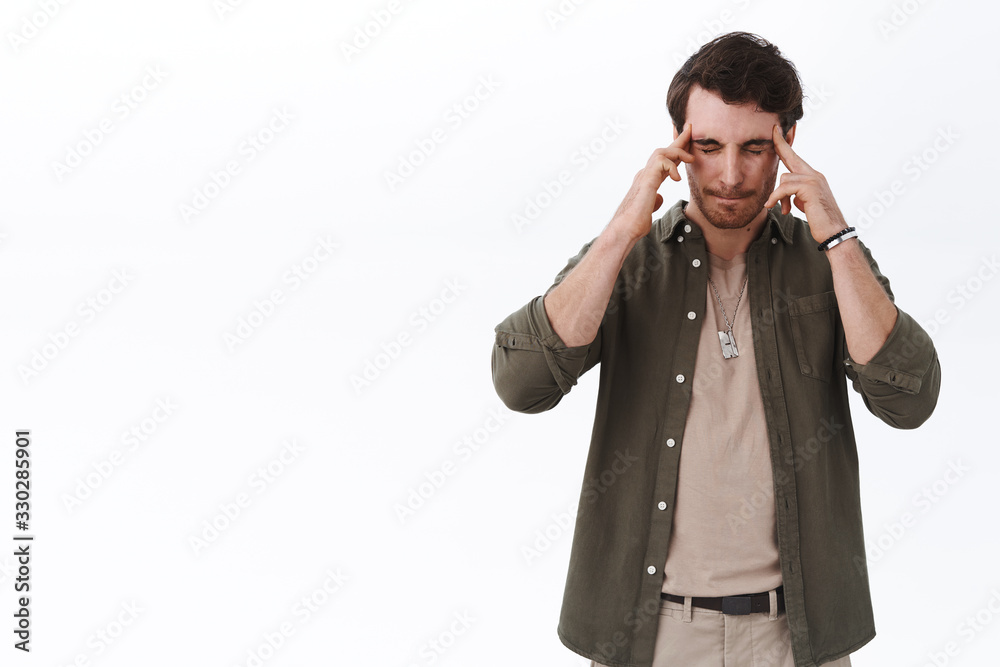 Portrait of young man suffering migraine, massaging temples as close eyes and grimace from pain, feel dizzy or unwell, have painful headache, need focus on task, thinking focused, white background Portrait of young man suffering migraine, massaging temples as close eyes and grimace from pain, feel dizzy or unwell, have painful headache, need focus on task, thinking focused, white background