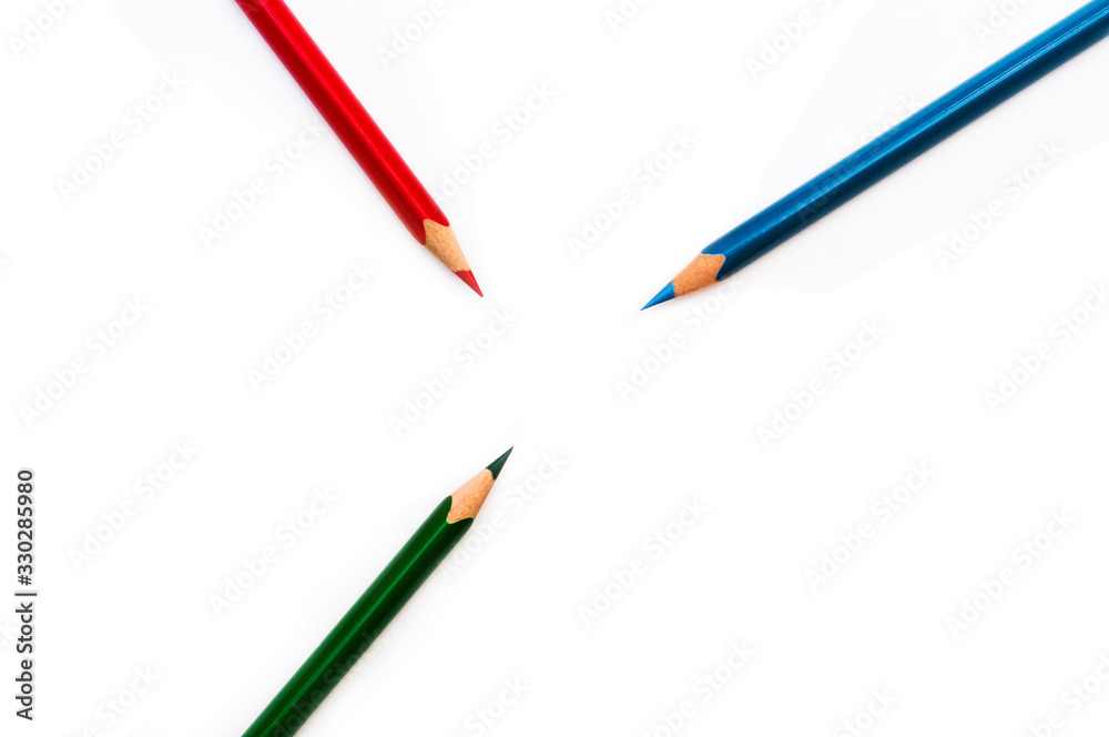 Naklejka premium colored pencils point to the center of the frame on a white background and contains empty space for your text