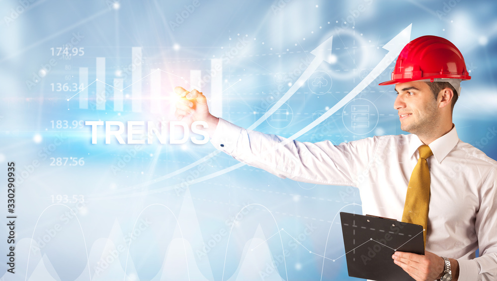 Young businessman with helmet drawing TRENDS inscription, modern business technology concept Young businessman with helmet drawing TRENDS inscription, modern business technology concept