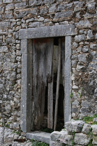 old wooden door in stone wall © Spyridon
