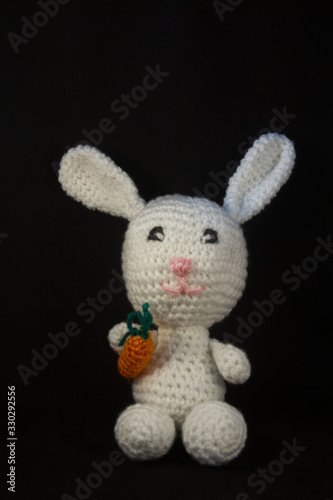 sweet white plush bunny with carrot in hand handmade on a black background