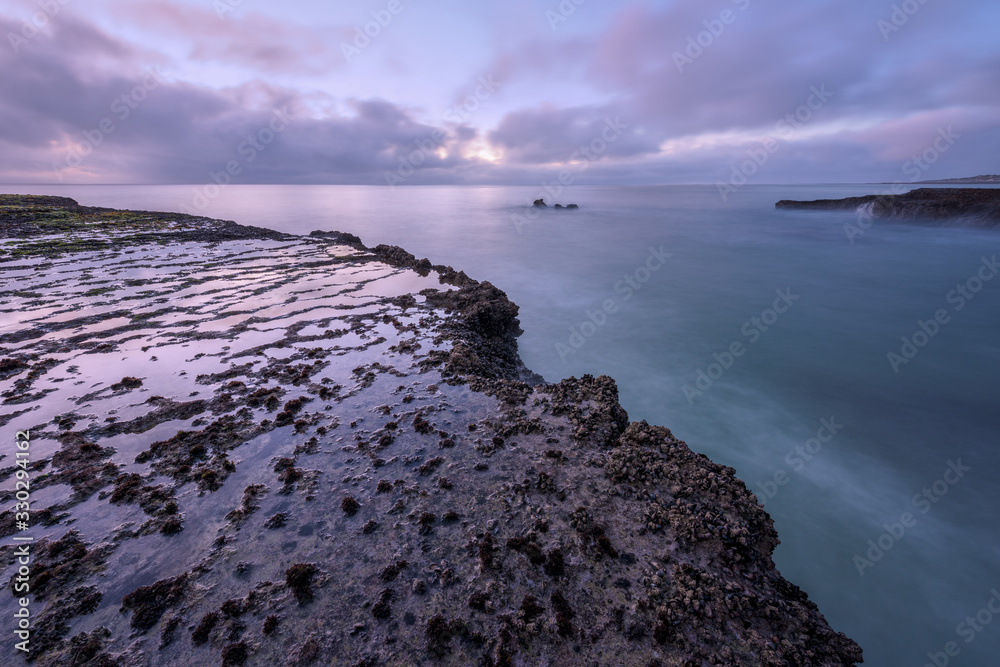 A beautiful early morning seascape with rocks in the foreground,  photographed on a stormy day before sunrise in Arniston, South Africa.