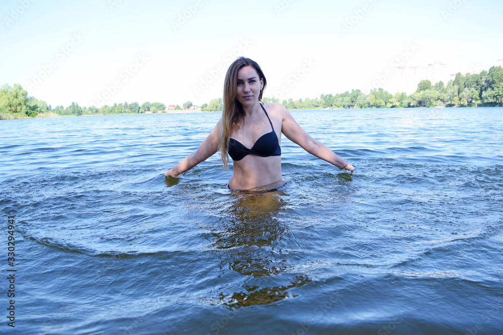 Young girl in a swimsuit on the lake makes waves of water