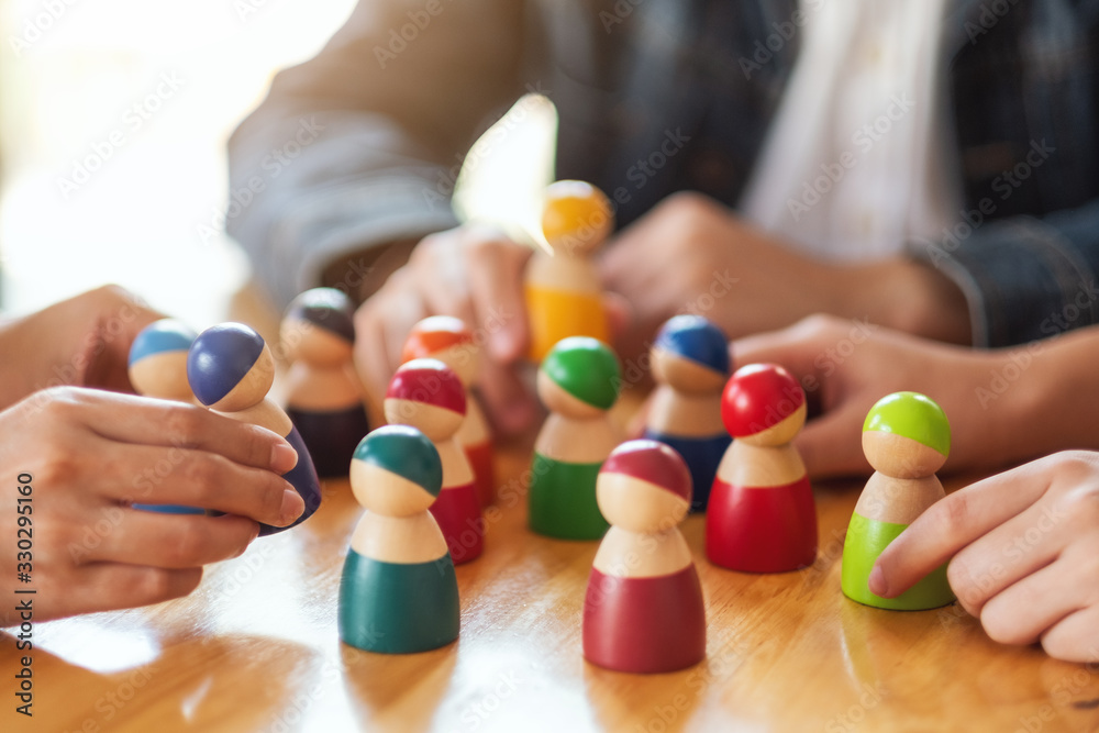 People choosing and picking up wooden figure from a group on the table People choosing and picking up wooden figure from a group on the table