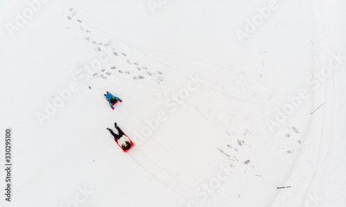 Top down view of two people tobogganing in snow