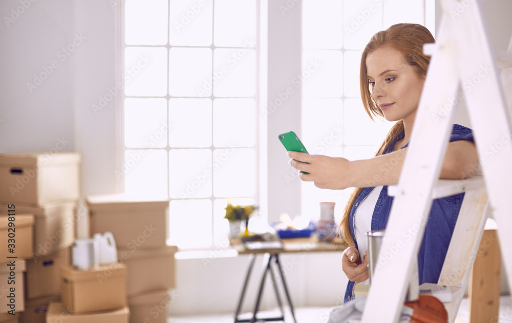 Beautiful young woman on a white wooden stepladder. Ready to repair the room. Women housework concept Beautiful young woman on a white wooden stepladder. Ready to repair the room. Women housework concept