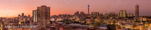 A beautiful and dramatic panoramic photograph of the Johannesburg city skyline, taken on a golden evening after sunset.